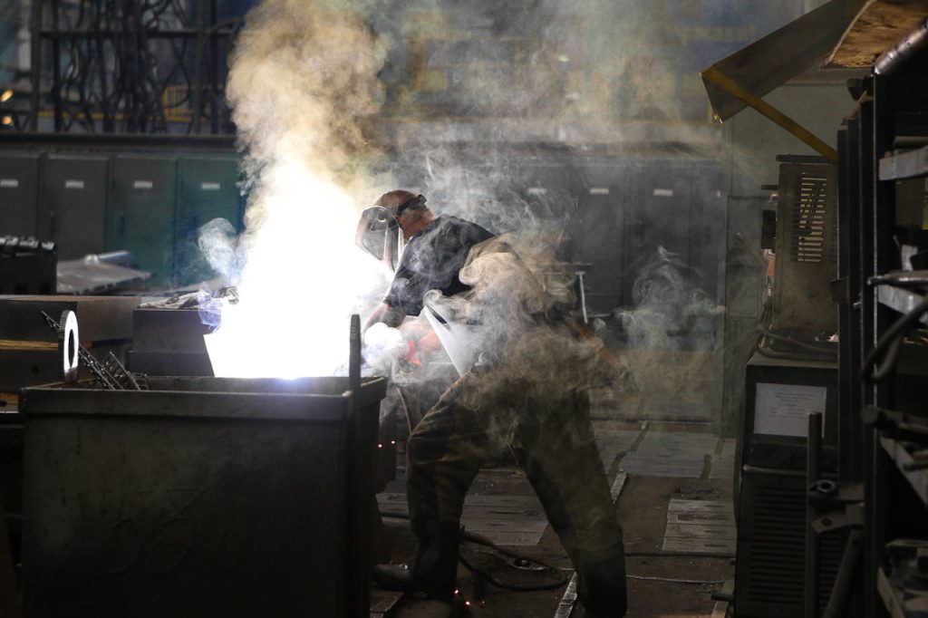 A skilled welder working with intense sparks and smoke in an industrial workshop, showcasing safety and precision.